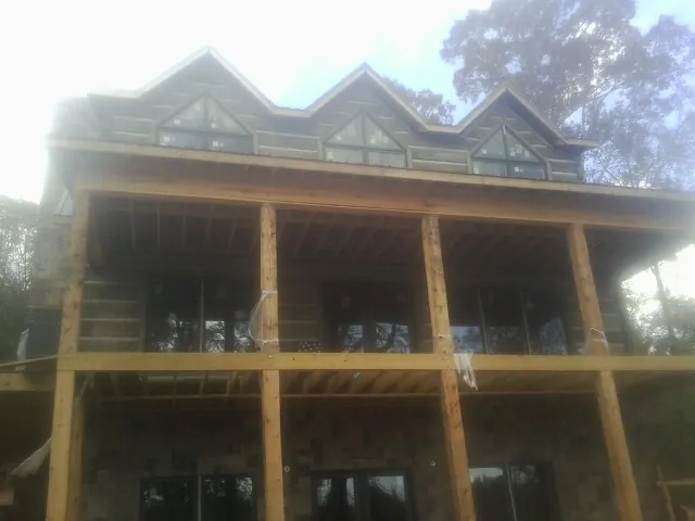Dormers and porch framing on a large log home under construction — Roof Coating work by our crew in Mission Hill