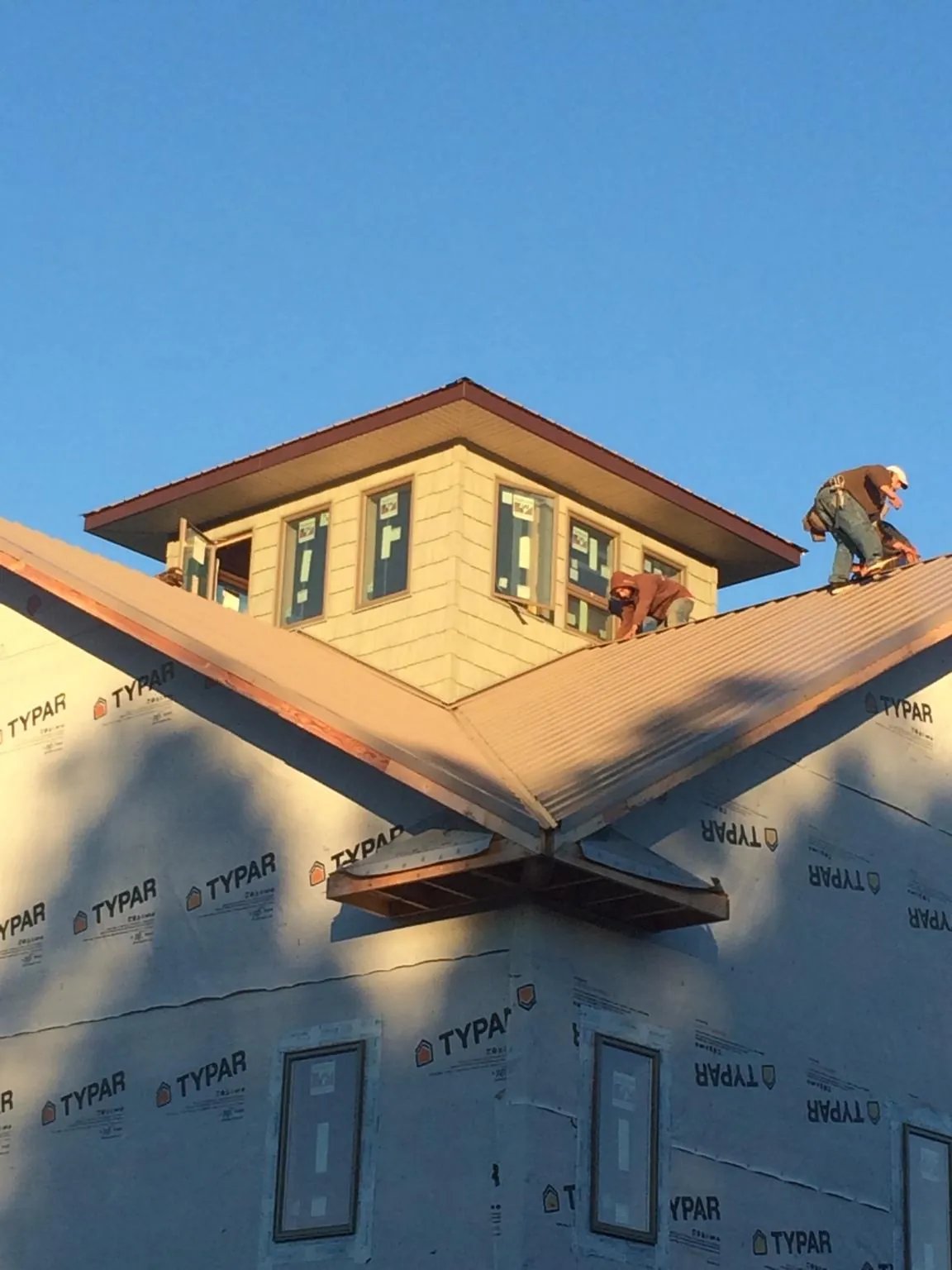 Roofers working around a rooftop cupola on a new metal roof at sunset — Roof Waterproofing in Mission Hill by Roofing Brothers